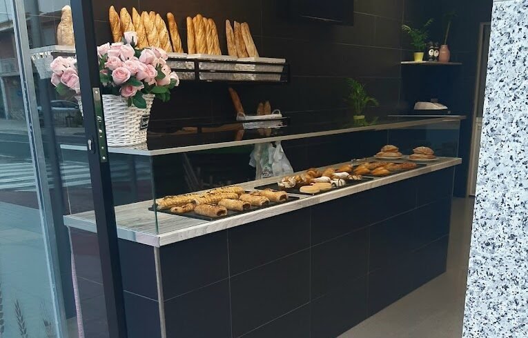 Mostrador con pan artesanal y bollería recién horneada en La Migaja, cafetería en Murcia.